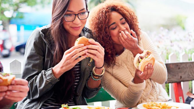 cargillplantafev20g.jpg Foto mostra duas jovens comendo hamburger ilustrando lançamento da Cargill